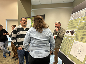 Aziz Ebrahimi with two members discussing a poster at the HTIRC Annual Meeting.